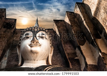 Ancient architecture of Buddhist temples in Sukhothai Historical Park. Statue of  Buddha Phra Achana at Wat Si Chum Temple under sunset sky. Thailand