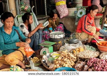 SIEM REAP, CAMBODIA - DEC 22, 2013: Unidentified Khmer women selling green grocery and spices at marketplace on Dec 22, 2013 in Siem Reap, Cambodia. Street food markets is popular tradition in asia
