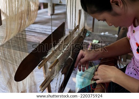 LUANG PRABANG, LAOS - 8 DEC, 2013: Unidentified woman weaving silk in traditional way at manual loom Laos