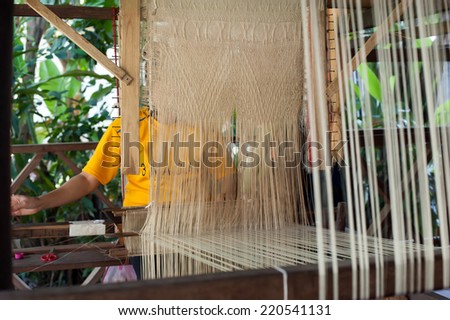 Woman weaving silk in traditional way at manual loom. Laos