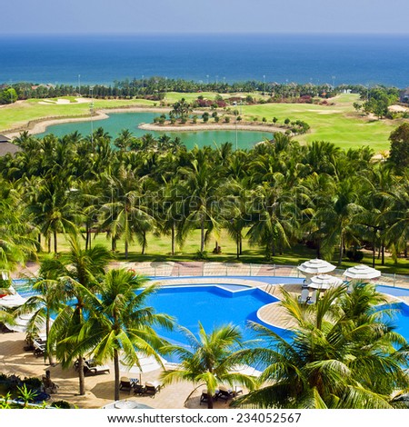 Amazing top view on swimming pool and golf field at tropical luxury hotel near ocean