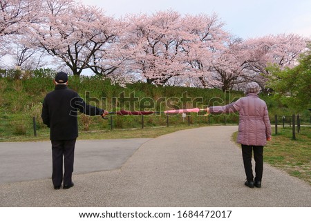 Social distancing (6 feet / 2 meters) to avoid the spread of coronavirus (COVID-19). Two people stand apart holding two umbrellas. A new concept along with elbow bumping. New normal.