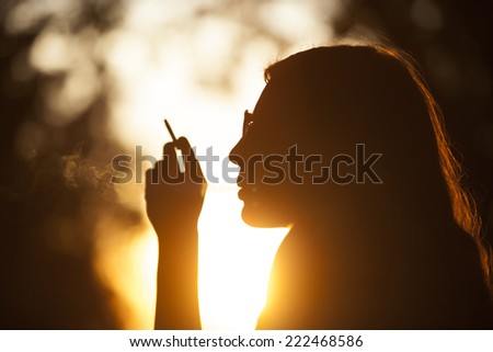 Young Girl Smoking In Park At Sunset