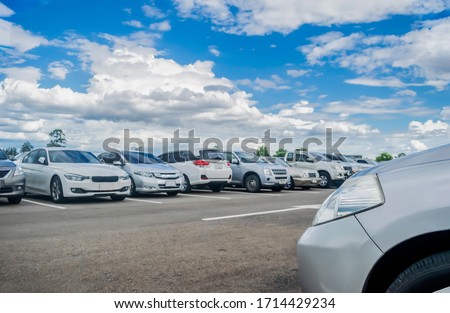 Car parking in large asphalt parking lot with beautiful sky background. Outdoor parking lot with nature fresh ozone and green environment of travel transportation business concept