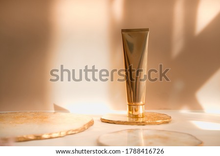 Golden cosmetic tube light pastel color background, lights and shadows. Natural minimalism look, clean concept. Minimal styling, still life. Beauty blogging, branding layout,  skin care ad mock up