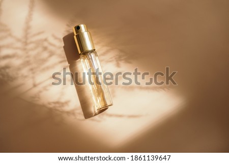 Small perfume bottle on warm pastel and golden colors table. Commercial, brand packaging mockup. Copy space. Refillable travel size. Product photography