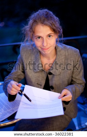 young business woman writing on a contract, at night