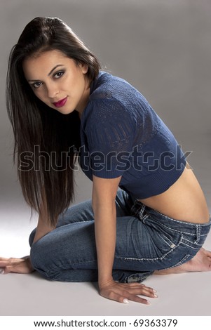 a beautiful young pretty hispanic woman kneeling on the floor.