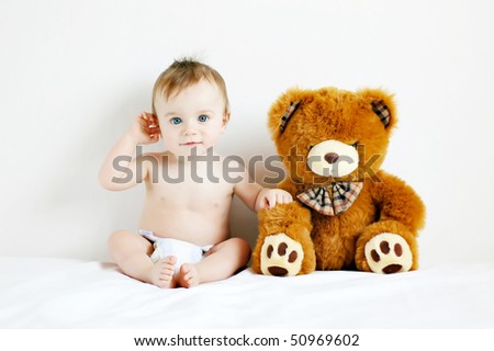 Little boy sitting next to a teddy bear