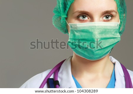 Close-up portrait of serious nurse or doctor in green mask over grey background