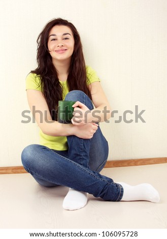 Happy casual girl sitting cross-legged with mug indoors