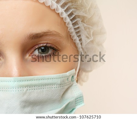 Portrait of serious young woman doctor with mask and cap