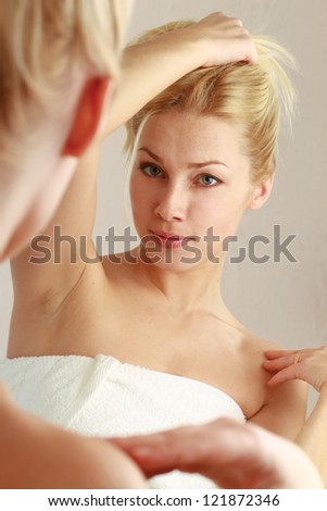 Woman caring of her beautiful skin on the face standing near mirror