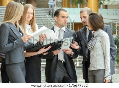Portrait of  business people standing in the office looking into folder with business plan