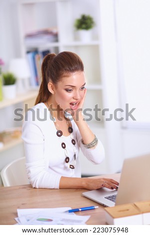Portrait of a businesswoman sitting at a desk with a laptop, isolated