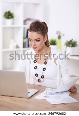 Portrait of a businesswoman sitting at a desk with a laptop, isolated