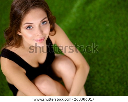 Woman sitting with crossed legs on the green grass .