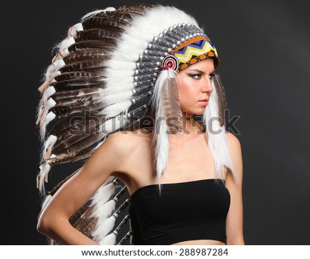 Beautiful woman in native american costume with feathers .