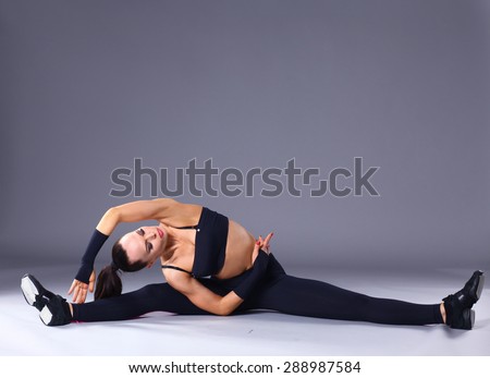 Young attractive female fitness woman performing a twine .