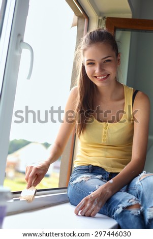 Woman with a paintbrush carefully finishing off around a window frame