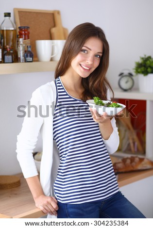 Young woman eating salad and holding a mixed salad .