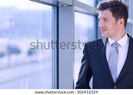 Portrait of businessman standing near window in office .