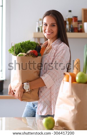 Young woman holding grocery shopping bag with vegetables .