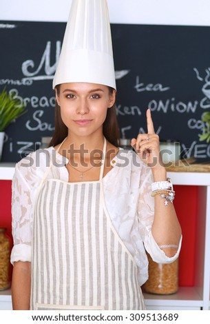 Chef woman portrait with  uniform in the kitchen and pointing up