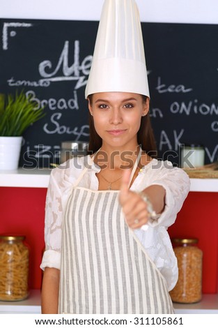 Chef woman portrait with  uniform in the kitchen and showing ok
