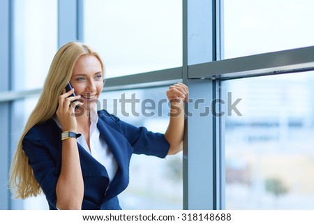 Businesswoman standing against office window holding documents in hand