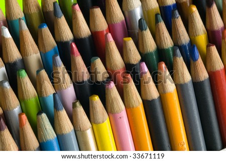 Colored pencil set used by an artist, points are not sharp, wide array of colors, angled view.