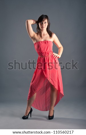 Beautiful woman with red dress against grey background. Full body portrait.