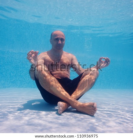 Underwater portrait of man in yoga position inside a swimming pool.