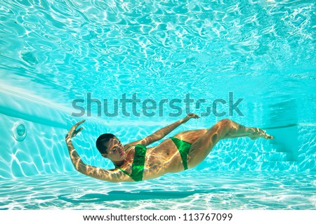 Underwater woman portrait with green bikini in swimming pool. Full body.