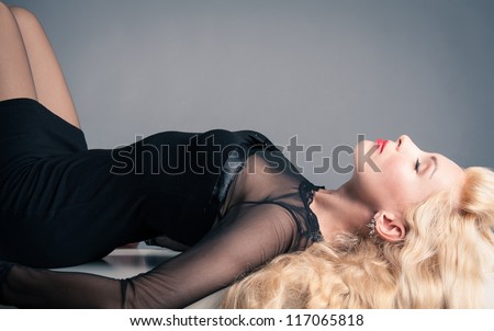 Elegant blonde woman profile with closed eyes and black dress.