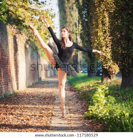 Young beautiful ballerina dancing outdoors in a narrow path. Ballerina Project.