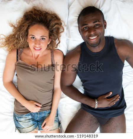 Happy young couple lying in bed, top view.