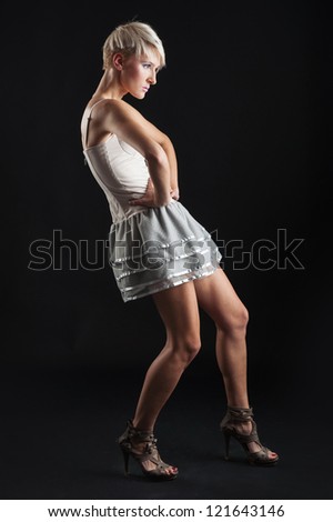 Young girl portrait with short dress isolated against black background. Full body static pose.