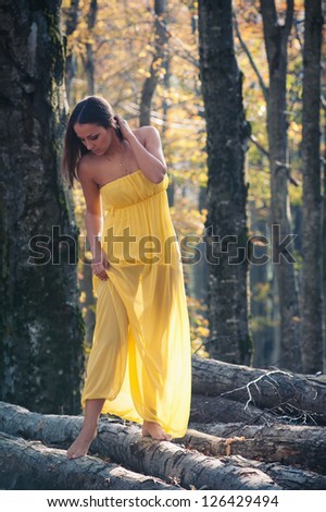 Beautiful young woman outdoors with yellow dress in the woods portrait.