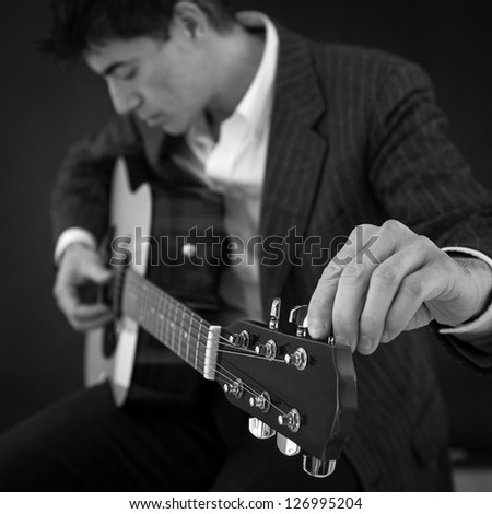 Man according guitar against black background. Black and white image. Shallow depth of field.