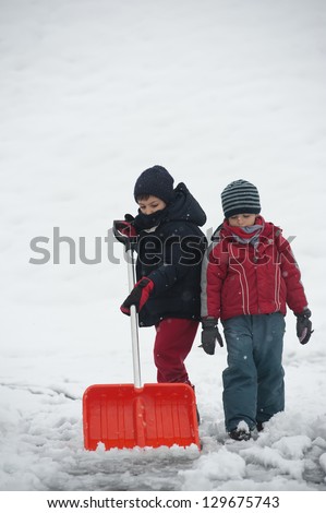 Young kids shoveling snow off sidewalk.