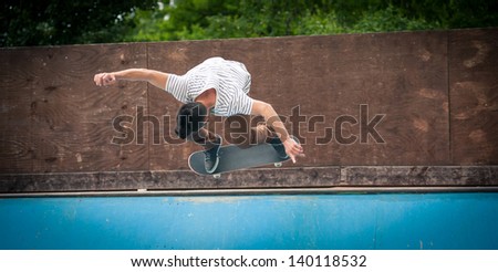 Skateboarder jumping in halfpipe at skate park.