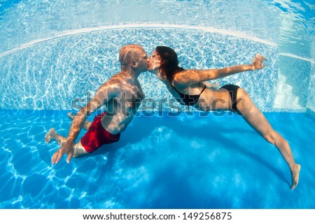 Underwater couple kissing in swimming pool.