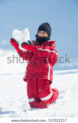 Young kid having fun in the snow with snowball.