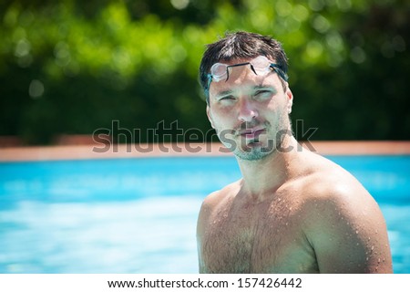 Portrait of a handsome man with goggles in swimming pool.