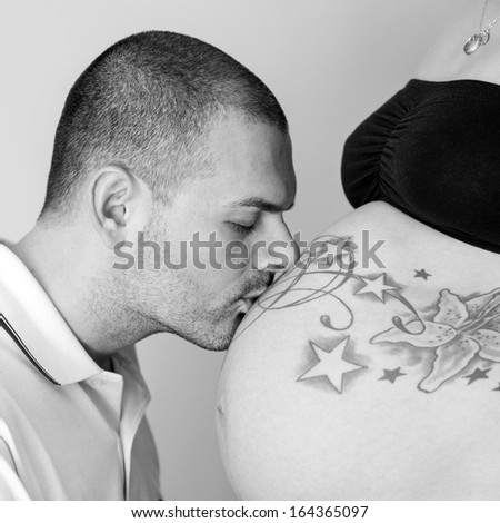 Man kissing pregnant woman belly. Black and white image.