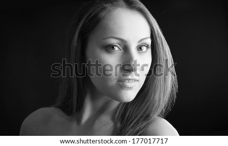 Intense woman close up portrait against dark background, black and white image.