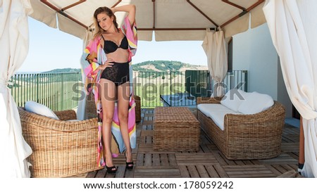 Beautiful woman full body portrait wearing black lingerie in a gazebo.