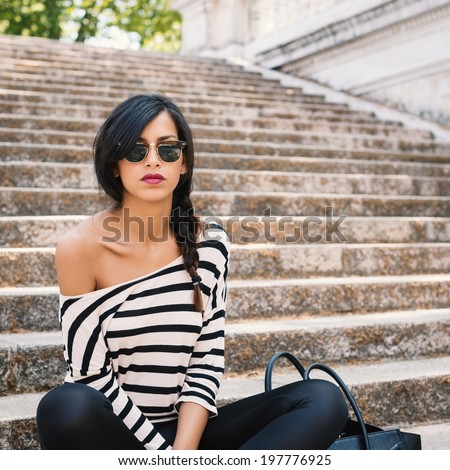 Young beautiful brunette woman portrait outdoors sit on stairs.