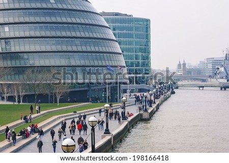 LONDON - APRIL 10, 2014: People walking close to City Hall. The building has a bulbous shape to reduce its surface area and improve energy efficiency.